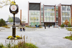 A clock with the CCAA logo sits in a courtyard at Centennial College